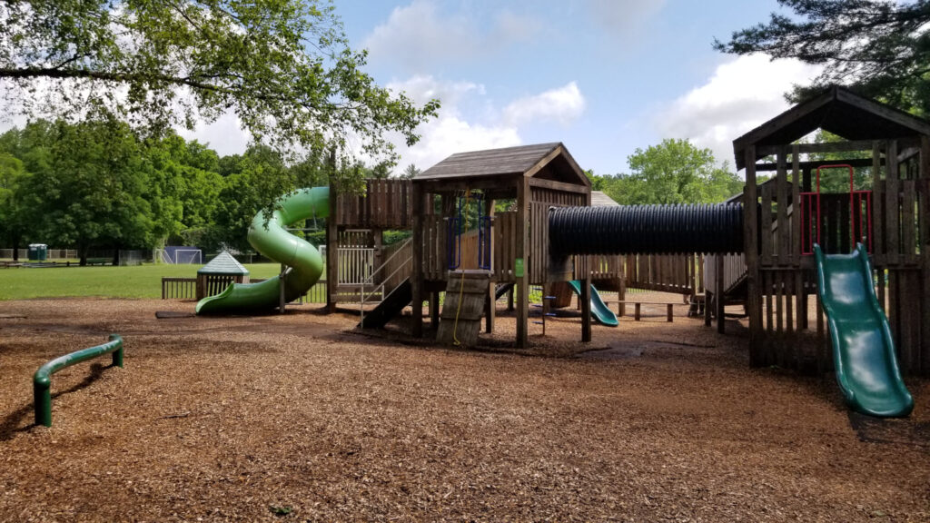 a mid-distance view of a wooden playground with slides and platforms